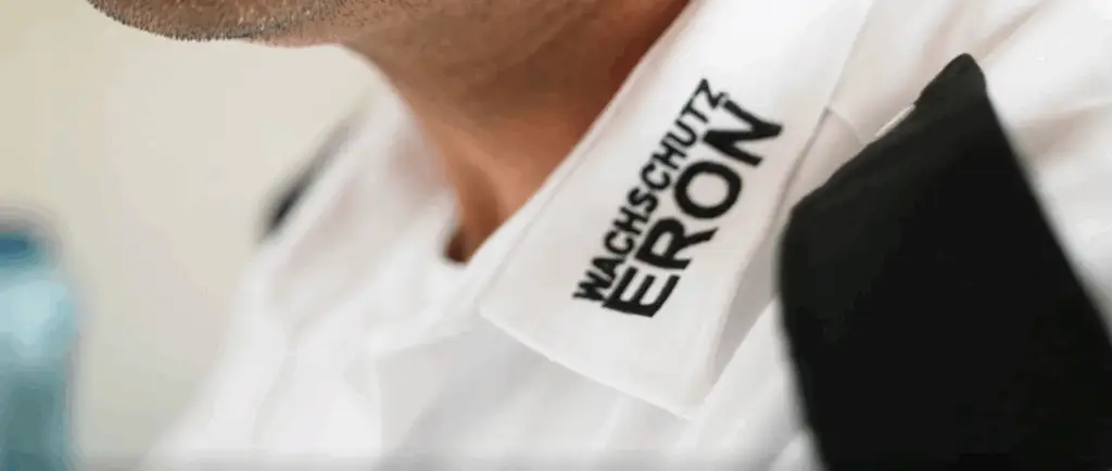 Detailaufnahme der Dienstkleidung von Eron Wachschutz Bielefeld – Sicherheitsdienst-Mitarbeiter mit sichtbarem Firmenlogo auf der Schulterklappe des zertifizierten IHK-Meisterbetriebs.