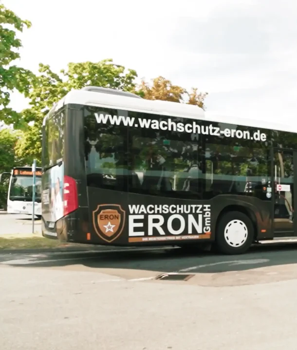 Bus mit Werbung von Eron Wachschutz Bielefeld auf einem Parkplatz im Stadtgebiet. Unsere Leistungen für ihr Unternehmen.
